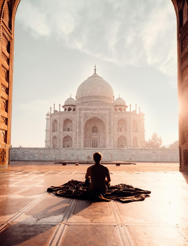 Yoga India A person meditates at sunrise facing the iconic Taj Mahal, capturing serenity and majesty.
